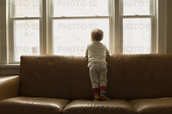 Caucasian boy looking out living room window