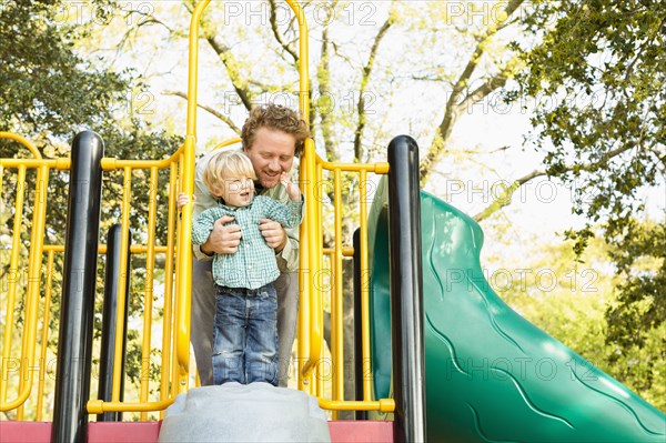 Caucasian father and son playing on play structure