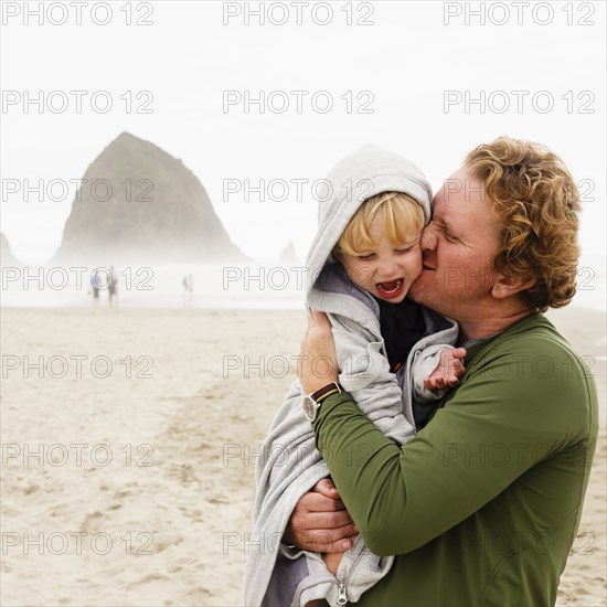 Caucasian father kissing son on beach