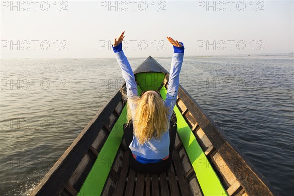 Caucasian woman cheering in canoe on lake