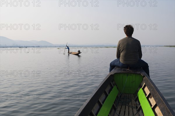 Caucasian man sitting on canoe on rural lake