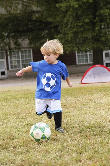 Caucasian boy playing soccer in field