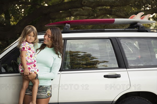 Mother holding daughter at car