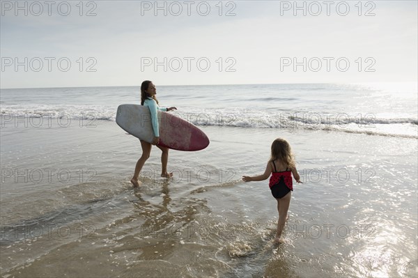 Mother and daughter playing in waves on beach