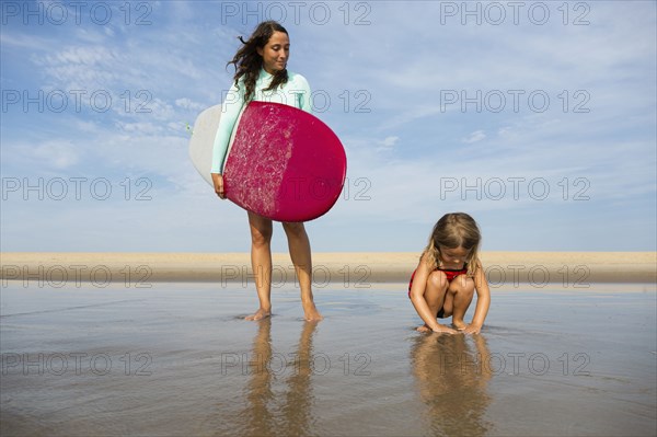 Mother and daughter playing in waves on beach