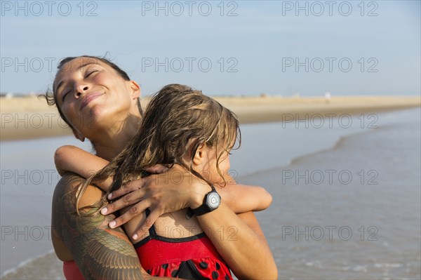 Mother and daughter hugging on beach