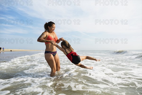 Mother and daughter playing in waves on beach