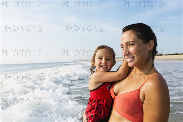 Mother holding daughter on beach