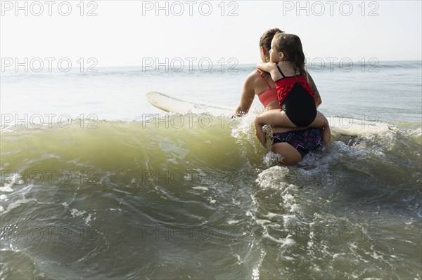 Mother and daughter surfing in waves