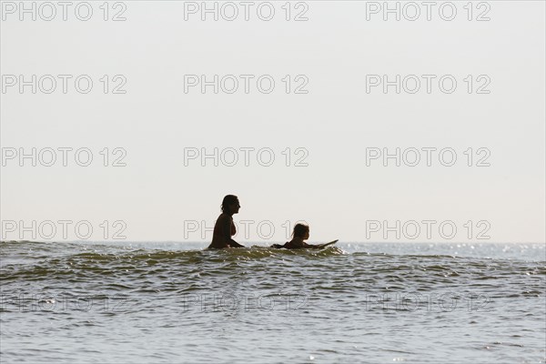 Mother and daughter surfing in waves