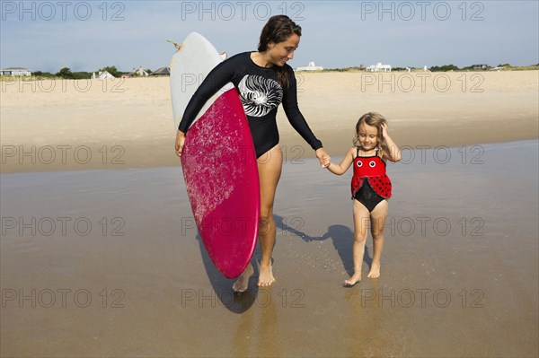 Mother teaching daughter to surf in ocean