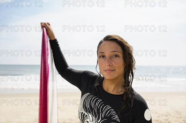 Hispanic surfer holding surfboard on beach