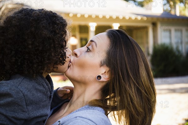 Mother kissing son outdoors