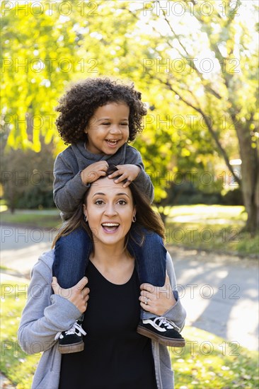 Mother carrying son on shoulders outdoors