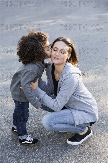 Boy kissing cheek of mother outdoors