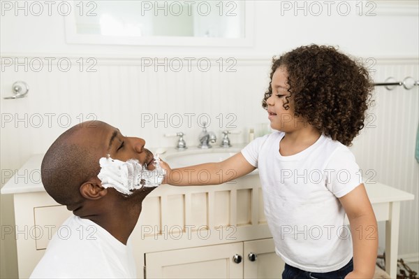 Boy helping father shave in bathroom