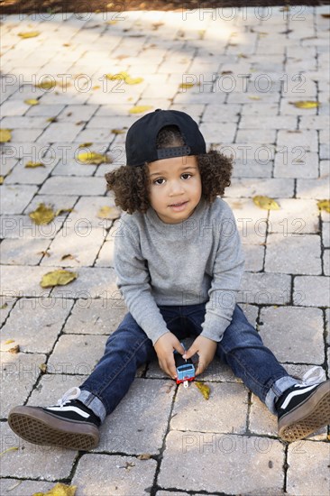 Mixed race boy sitting on brick patio