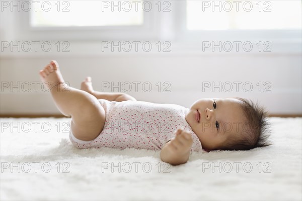 Mixed race baby girl laying on floor