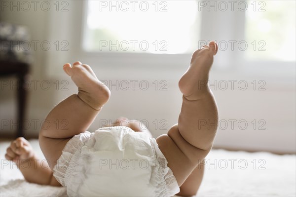 Mixed race baby girl laying on floor