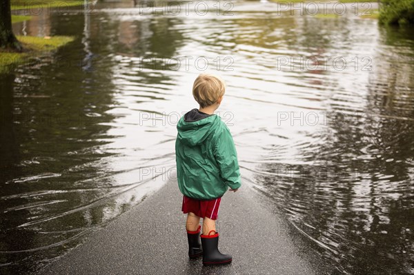 Caucasian boy wearing puddles near flood