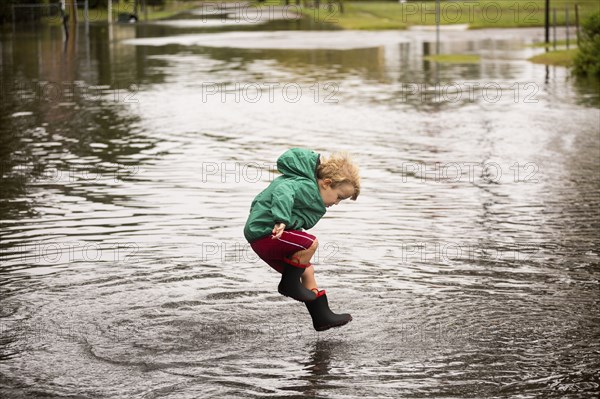 Caucasian boy jumping in puddle