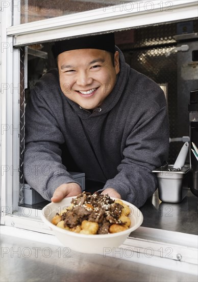 Proud Asian man showing bowl of food at food truck