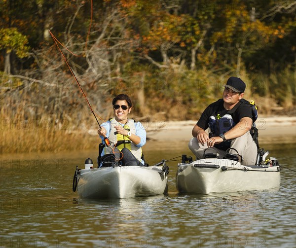 Couple fly fishing in kayaks on river