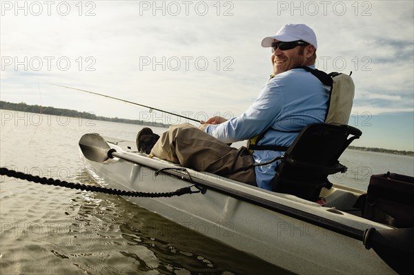 Caucasian man fly fishing in kayak on river