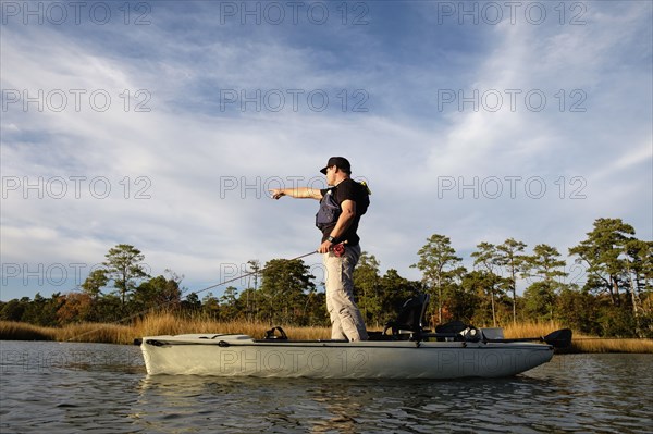 Caucasian man fly fishing in kayak on river