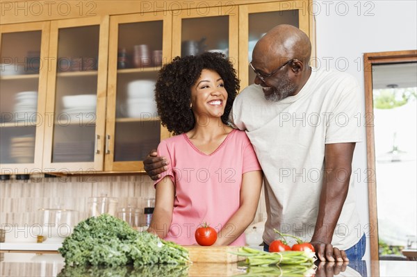 Black father and daughter hugging in kitchen