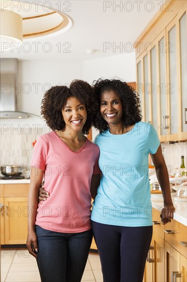 Black mother and daughter hugging in kitchen