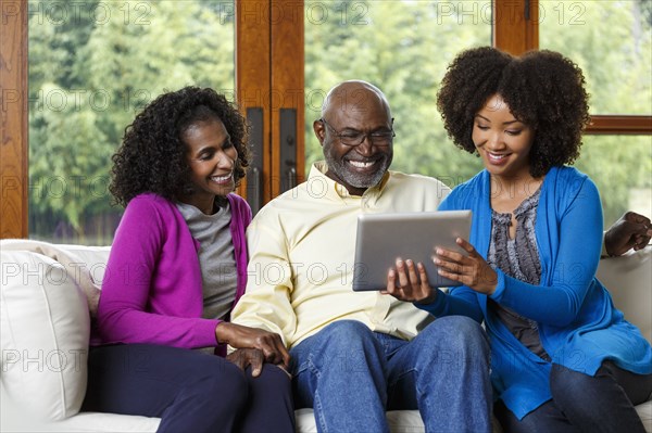 Black family using digital tablet on sofa