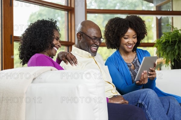 Black family using digital tablet on sofa