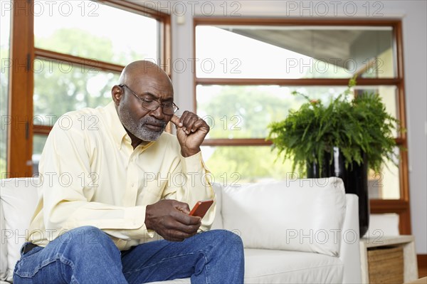 Black man texting with cell phone on sofa