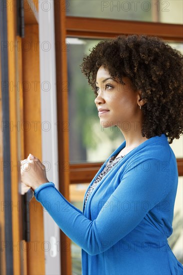 Pensive Black woman looking out window