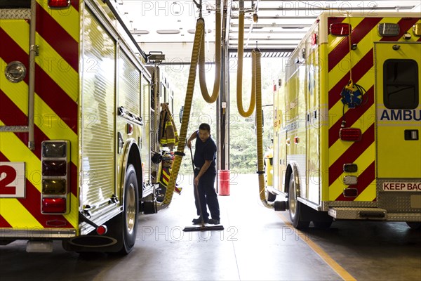 Chinese fireman sweeping floor near fire trucks