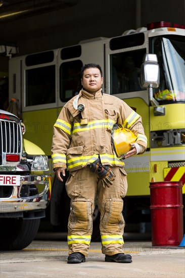 Serious Chinese fireman posing near fire trucks