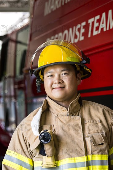 Smiling Chinese fireman standing near fire truck