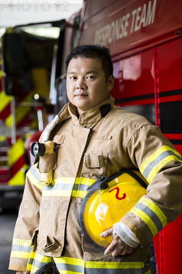 Serious Chinese fireman standing near fire truck