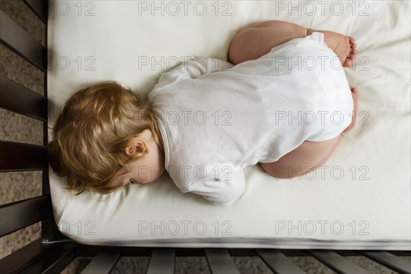 Caucasian baby boy sleeping in crib