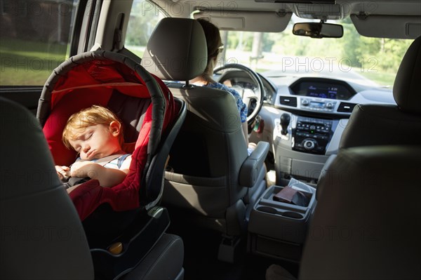 Caucasian mother driving car with baby son in car seat