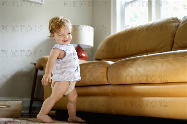 Caucasian baby boy walking near sofa