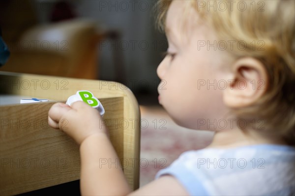 Caucasian baby boy holding toy letter