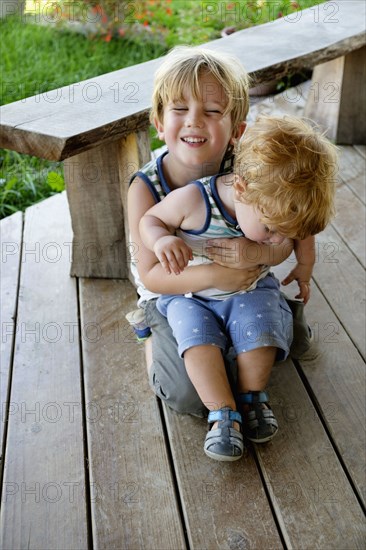 Caucasian brother hugging baby brother