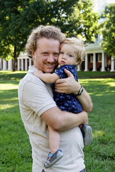 Caucasian father holding baby son outdoors