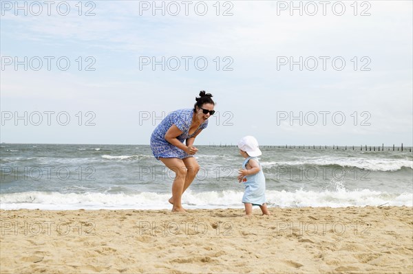 Caucasian mother and baby son playing at beach