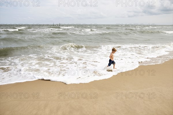 Caucasian boy running in waves at beach