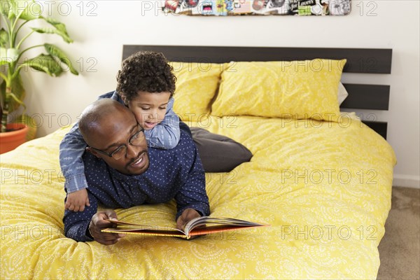 Father reading book to son on bed