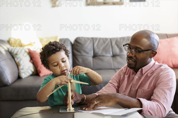 Father and son building model windmill in livingroom