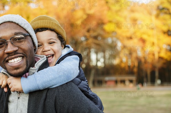 Father carrying son piggyback in park